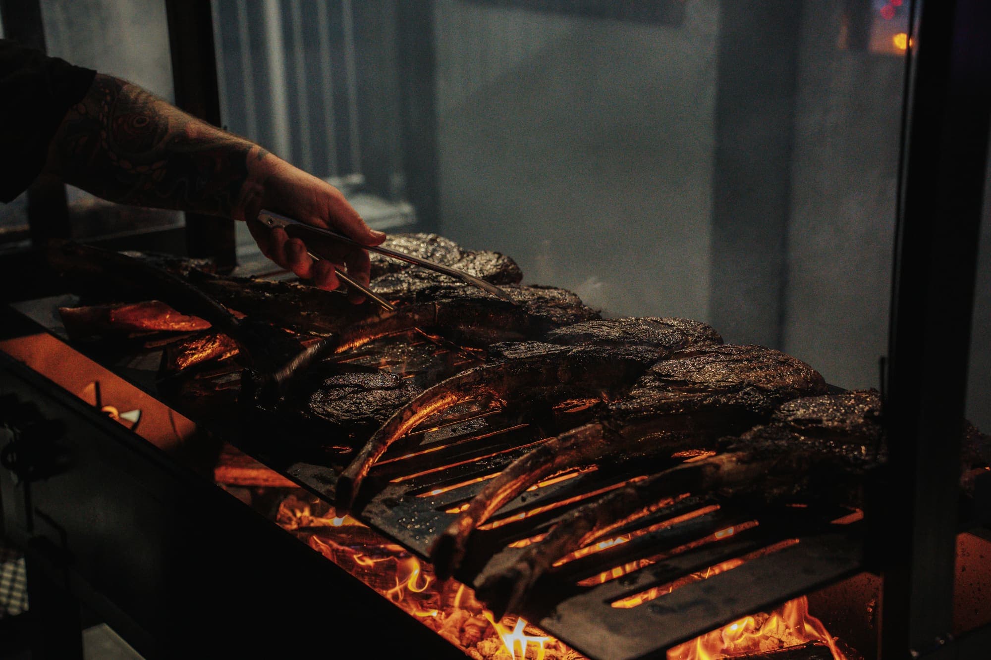 Tomahawk steaks lined up over glowing coals